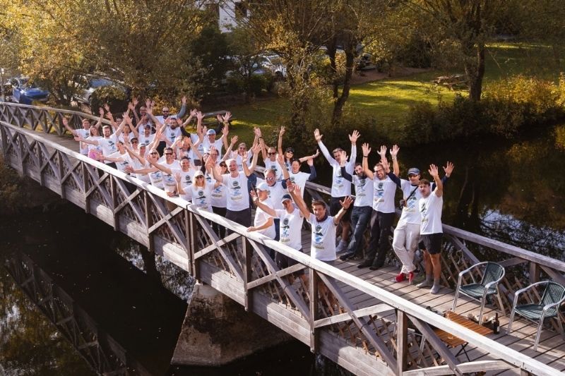 group picture of participants in a hike standing on a bridge with their hands up
