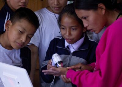 A group of students attentively examines a small, illuminated handheld microscope